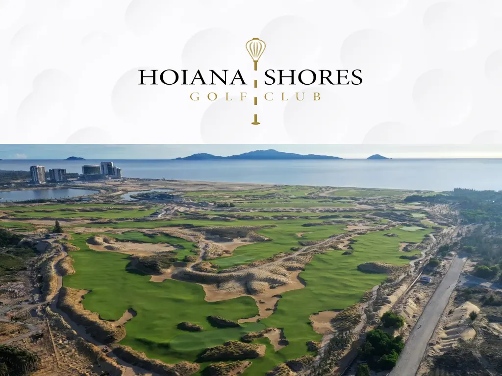 Cảnh Hoiana Shores Golf Club với sân golf xanh mướt trải dài giữa thiên nhiên, các lỗ golf được thiết kế đẹp mắt bao quanh bởi hồ nước và đồi đồi nền, người chơi golf đang tham gia trên sân, tạo nên không gian yên bình và sang trọng cho các tín đồ yêu thích môn thể thao này.