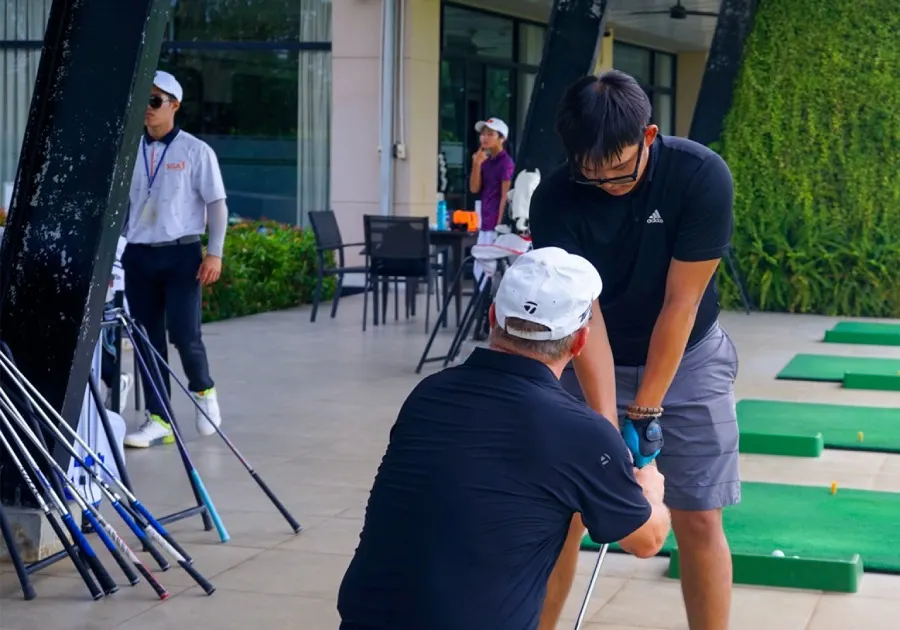 Image of a golf camp in Vietnam, with students practicing their swings on a large golf course surrounded by lush natural scenery and professional instructors guiding techniques in a relaxed environment.