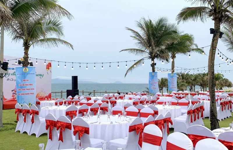 Hình ảnh một buổi gala dinner được tổ chức tại Hội An, với bàn tiệc trang trí sang trọng, ánh đèn lấp lánh và khách mời thưởng thức ẩm thực trong không gian lịch sử và lãng mạn của phố cổ.