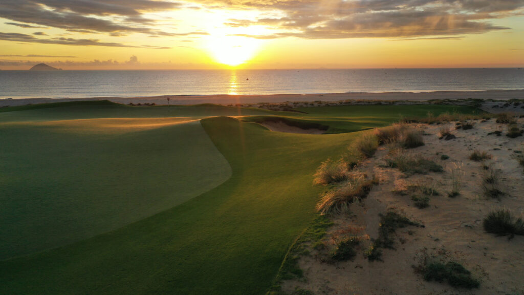 Golfer teeing off on a scenic hole overlooking the ocean at a Vietnam resort course