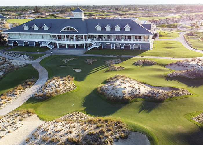 Golfer teeing off at Hoiana Shores Golf Club with ocean in background