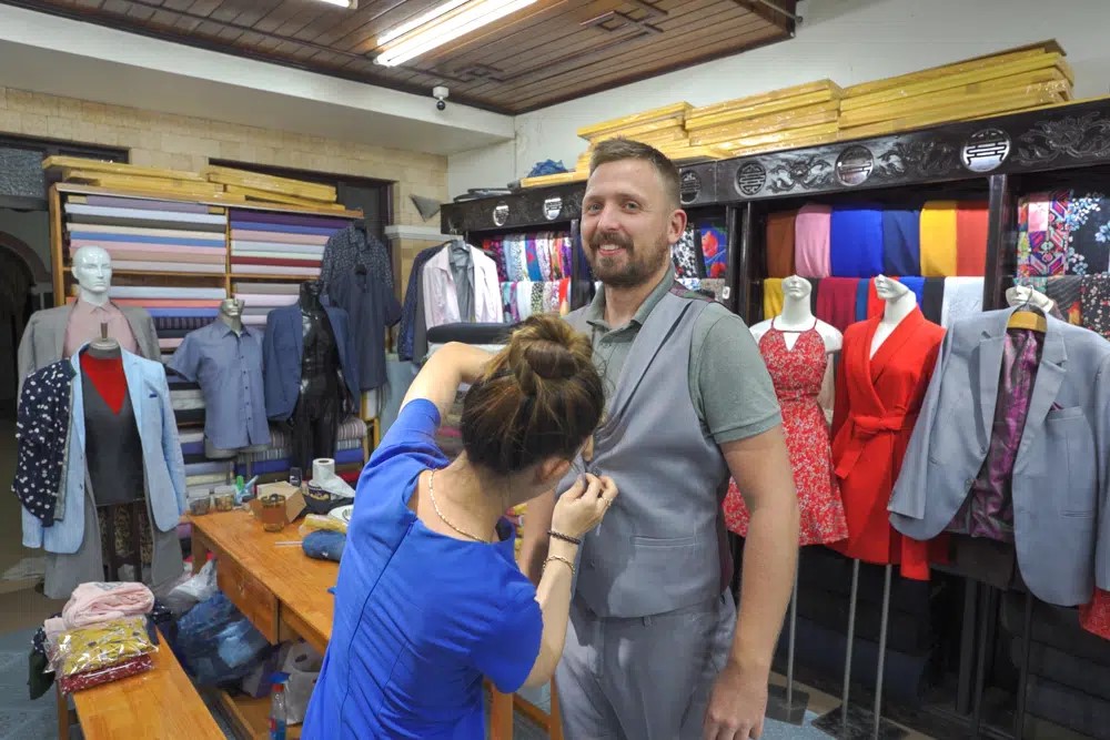 Tailor measuring a customer with a tape measure, highlighting the meticulous process behind custom tailoring