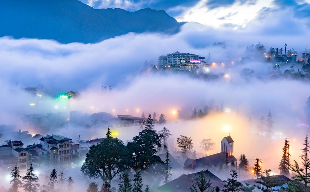 Panoramic view of Sapa showcasing terraced rice fields cascading down green hillsides with misty mountains in the background