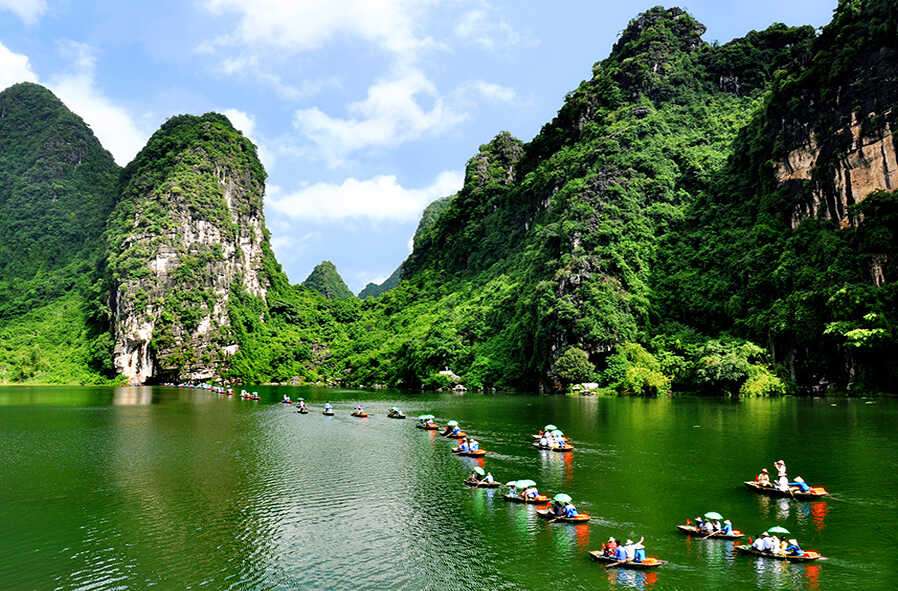 Breathtaking view of Ninh Binh with towering limestone karsts, lush green rice paddies, and a serene river winding through the picturesque landscape.