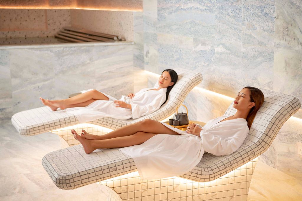 A guest enjoying a rejuvenating spa treatment at New World Hoiana Beach Resort, with a view of the ocean in the background.