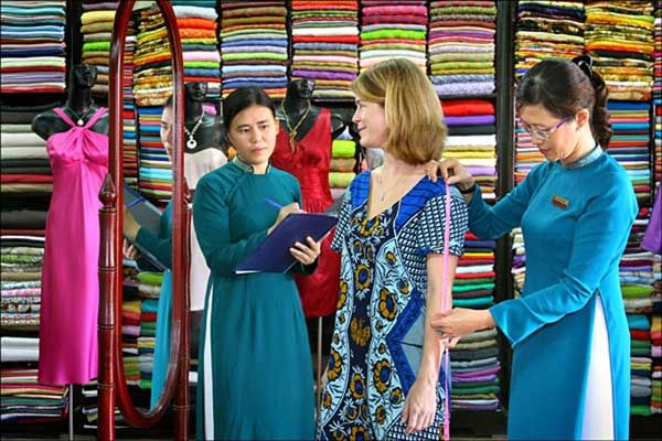 A tailor at B'lan Silk in Hoi An working on a silk garment, highlighting the shop's expertise in handling fine materials