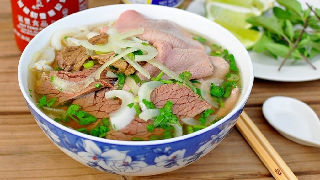 A bowl of traditional Vietnamese pho with beef, herbs, and noodles