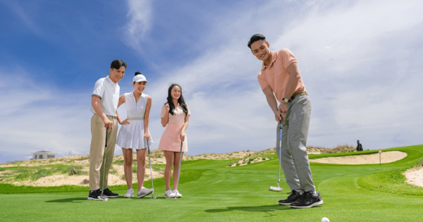 A family playing golf together on a green course in Vietnam, with parents guiding their children.