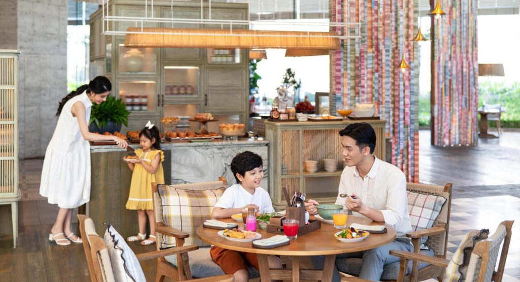 A family enjoying a meal at a restaurant within a golf resort, with a variety of dishes served.