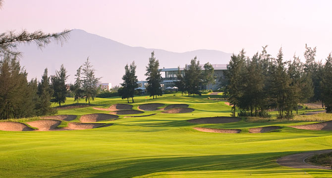 The well-manicured greens of Montgomerie Links Vietnam with a mountain backdrop.