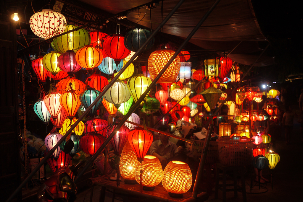 A display of colorful handmade lanterns and traditional souvenirs at a market in Hoi An.