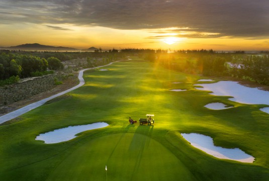 A tranquil golf course at dusk, with a few golfers enjoying the peaceful atmosphere.