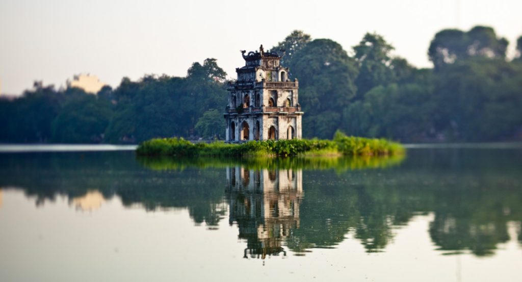 The iconic Hoan Kiem Lake in Hanoi with its ancient temple and bustling cityscape.