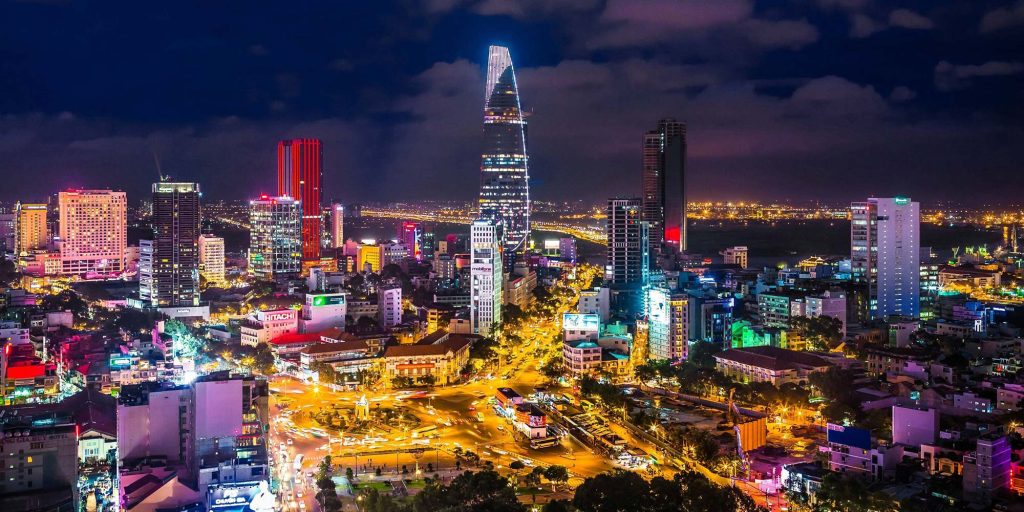 Ho Chi Minh City skyline at night, with brightly lit skyscrapers and bustling streets.