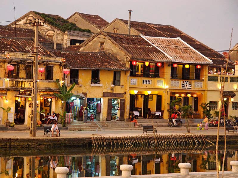 Lantern-lit streets of Hoi An, with colorful old buildings and reflections on the river.