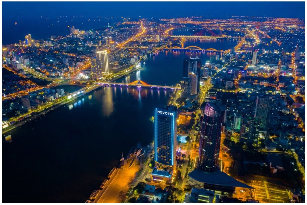 Aerial view of Danang’s golden beaches with modern cityscape in the background.