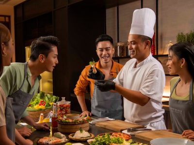 A couple participating in a cooking class at Hoiana Resort & Golf with professional chefs.