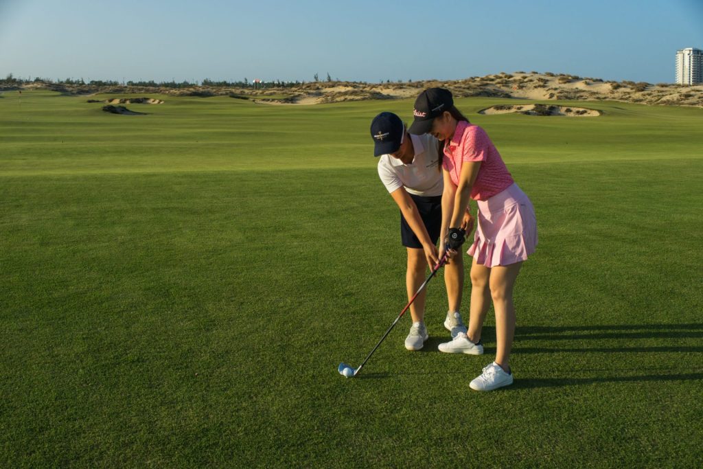 A family playing golf together at Hoiana Resort & Golf, with a picturesque landscape in the background.