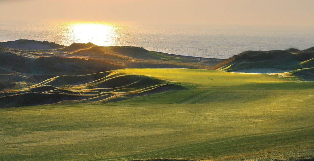 A focused golfer preparing for a swing at twilight, with a beautiful backdrop of the setting sun.