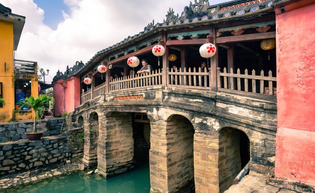 The historic Japanese Covered Bridge in Hoi An, surrounded by lanterns and greenery.