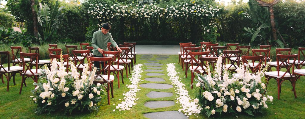 A romantic outdoor wedding setup on a lawn by the beach with floral arches.