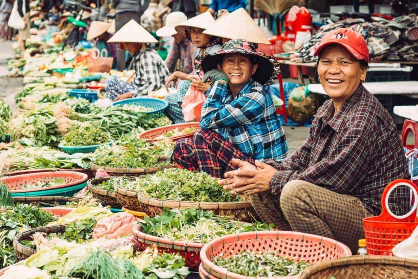 A close-up of a vendor at Hoi An Market offering colorful lanterns, textiles, and local spices to customers.