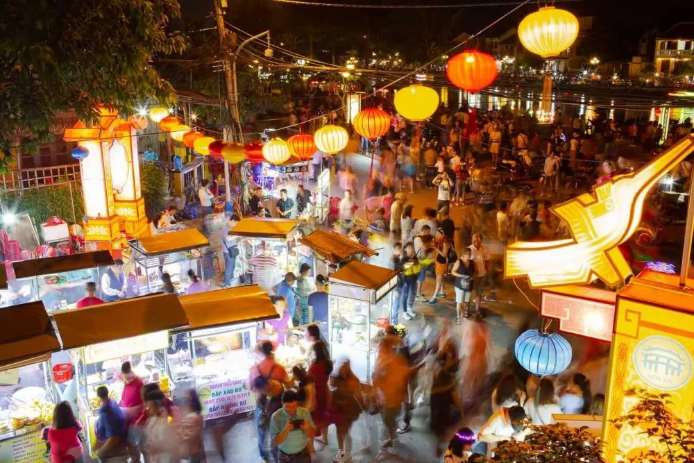 A bustling scene at Hoi An Market with vendors selling traditional Vietnamese foods, souvenirs, and handmade goods.