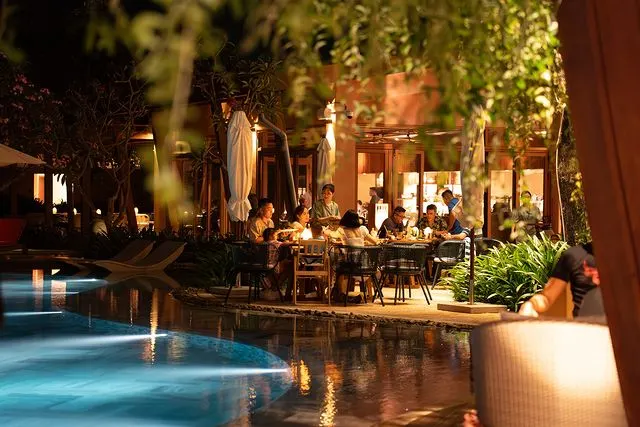 Interior view of a trendy bar in Hoi An, showcasing vibrant décor, cocktails on the counter, and guests enjoying a relaxing evening atmosphere.