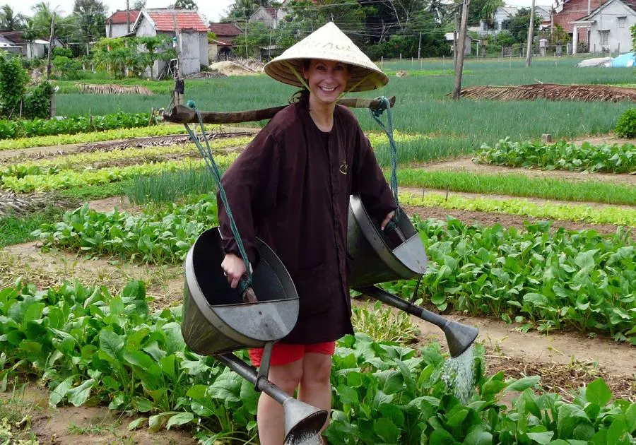 Farmers working in Tra Que Vegetable Village, Hoi An, planting fresh herbs amidst vibrant green rows of crops.