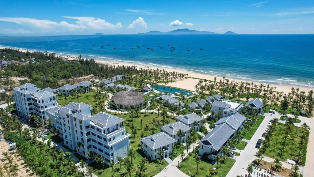 Ảnh chụp một khu nghỉ dưỡng lãng mạn ở Hội An, với hồ bơi ngoài trời và không gian xanh mát, lý tưởng cho các cặp đôi tận hưởng kỳ nghỉ yên bình — resort Hội An cho các cặp đôi.