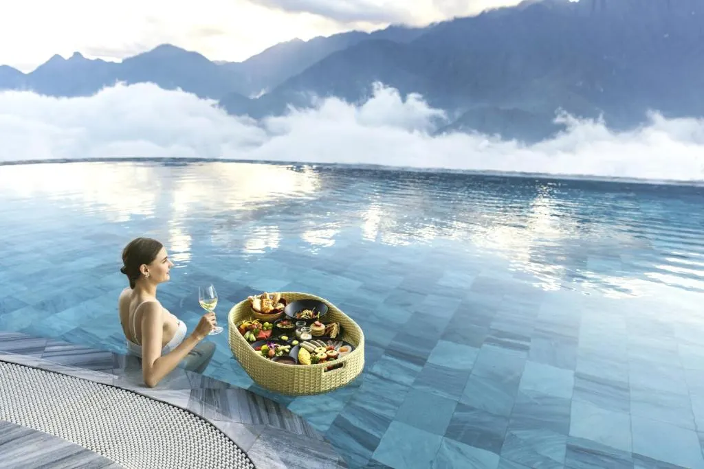 Luxury resort with infinity pool in Vietnam overlooking the ocean, surrounded by tropical greenery and modern architecture.
