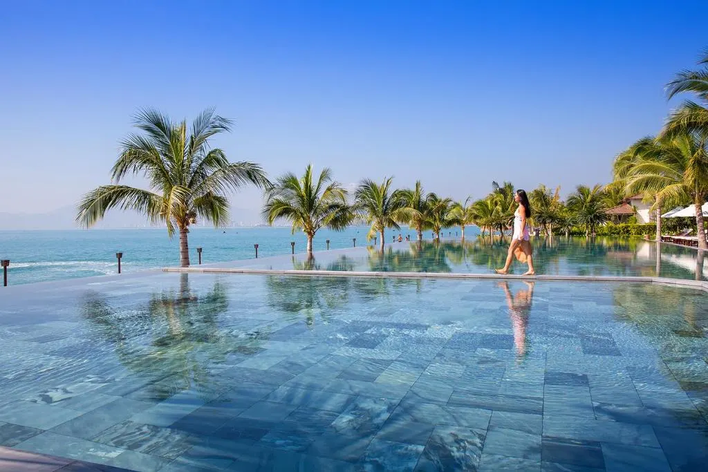 Luxury resort with infinity pool in Vietnam overlooking the ocean, surrounded by tropical greenery and modern architecture.