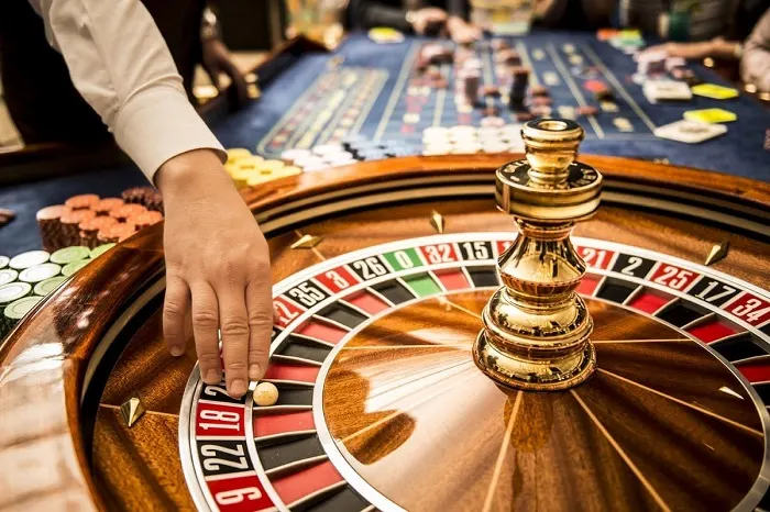 Người chơi đang tham gia các table games tại Việt Nam trong một sòng bài hiện đại với bàn chơi roulette và blackjack, ánh sáng rực rỡ và không khí sôi động.