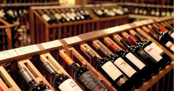 Interior view of a cozy wine shop in Hoi An with wooden shelves displaying a variety of wine bottles.