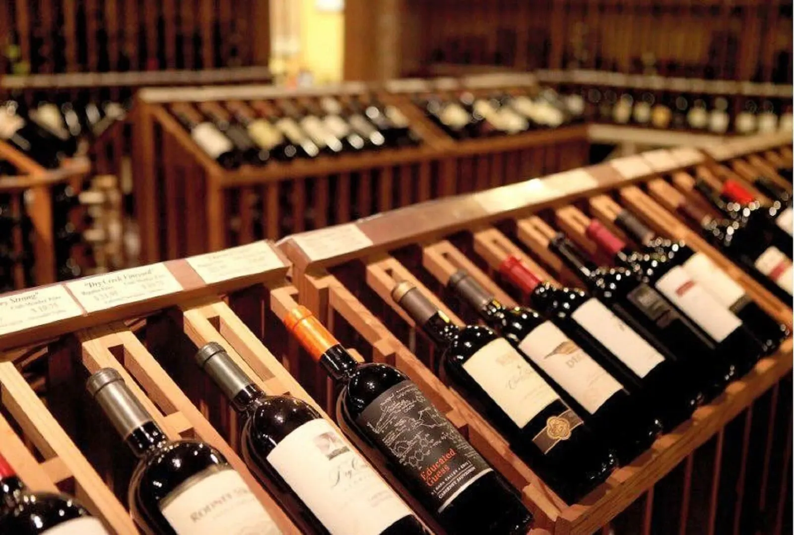 Interior view of a cozy wine shop in Hoi An with wooden shelves displaying a variety of wine bottles.