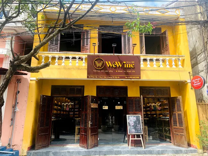 Interior view of a cozy wine shop in Hoi An with wooden shelves displaying a variety of wine bottles.