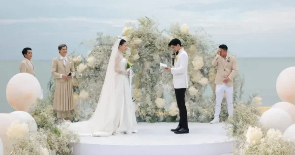 바다를 배경으로 로맨틱하게 꾸며진 베트남 리조트 웨딩 패키지 현장, 하얀 천과 꽃장식으로 장식된 야외 결혼식 세팅.