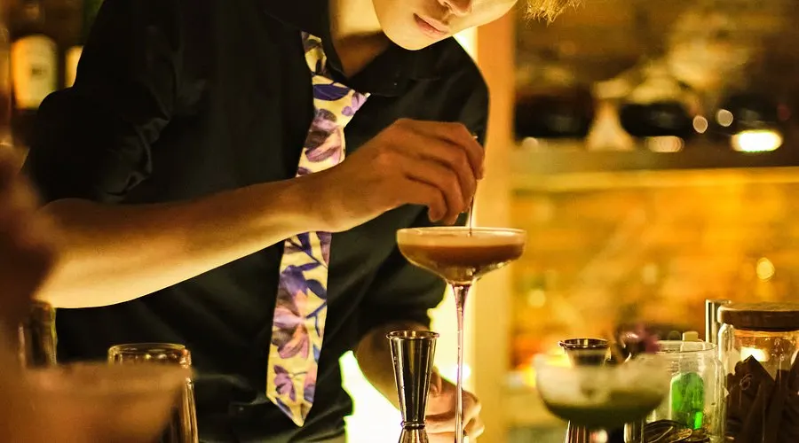 Quầy pha chế đầy màu sắc tại một cocktail bar tại Hội An, nơi du khách thưởng thức đồ uống thủ công trong không gian hiện đại pha nét cổ điển.