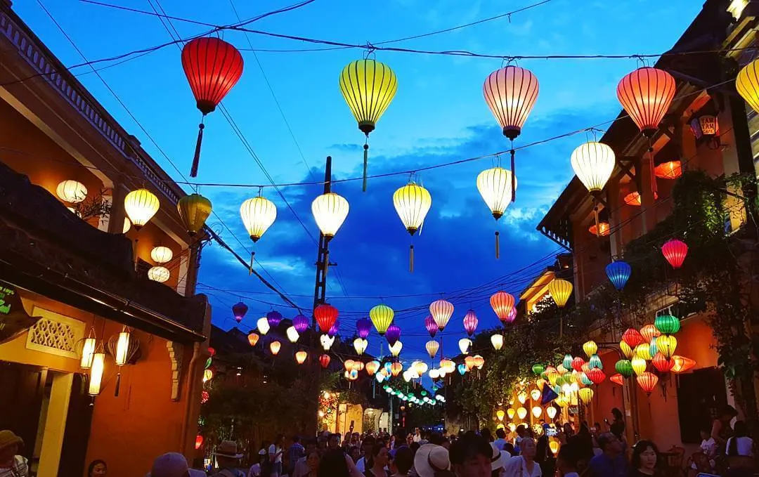 Du khách tận hưởng vẻ đẹp rực rỡ của phố cổ trong chuyến du lịch Hội An tháng 7, giữa những dãy nhà vàng cổ kính và sắc hoa giấy nở rộ.
