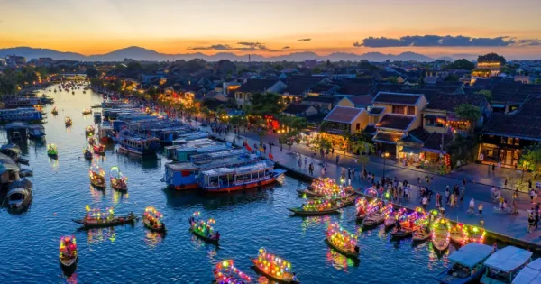 "Scenic view of Hoi An in July, with lanterns lighting up the ancient streets, lush greenery, and visitors strolling through the warm, vibrant atmosphere of summer."