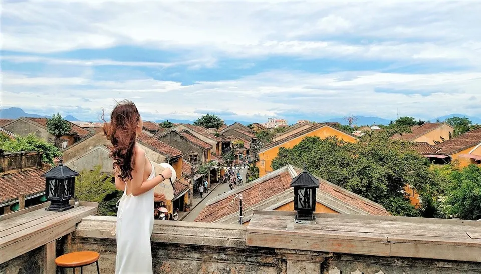 "Peaceful street scene in Hoi An in August, with golden sunlight, colorful lanterns, and locals going about their day in the historic ancient town."