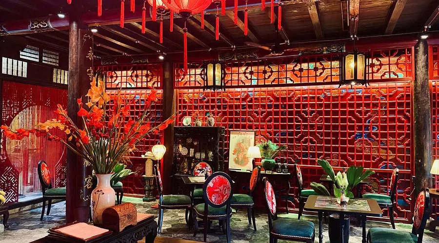 "Traditional Chinese restaurant in Hoi An with classic red lantern decor, round dining tables, and a menu featuring dim sum, Peking duck, and regional specialties."